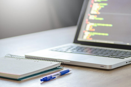Notepad, ballpoint pen, and laptop on office desk
